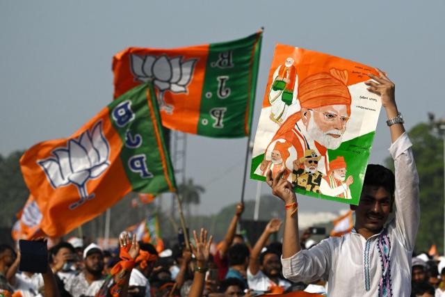 A Bharatiya Janata Party (BJP) supporter holding a poster of India's Prime Minister Narendra Modi attends a mass rally in Kolkata on March 14, 2026. (Photo by Dibyangshu SARKAR / AFP)