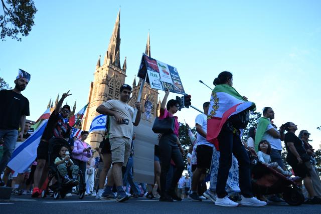 Members of the Iranian community in Australia hold flags and placards during a rally following US and Israeli attacks on Iran sparking the Middle East war, in Sydney on March 14, 2026. (Photo by SAEED KHAN / AFP)