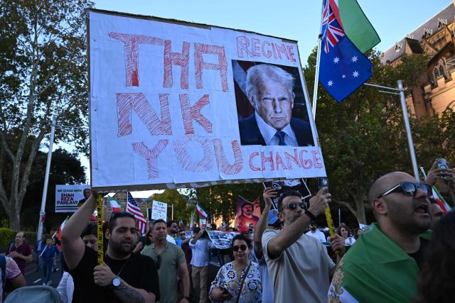 Members of the Iranian community in Australia hold flags and placards during a rally following US and Israeli attacks on Iran sparking the Middle East war, in Sydney on March 14, 2026. (Photo by SAEED KHAN / AFP)