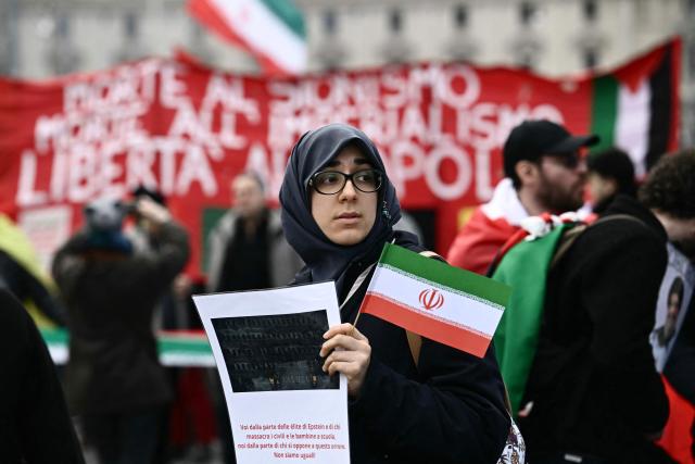 A demonstrator holds a flag of Iran while taking part in a rally organized by the "Social No" commitee to also mobilise support for a "No" vote in the justice referendum in Rome on March 14, 2026. (Photo by Filippo MONTEFORTE / AFP)