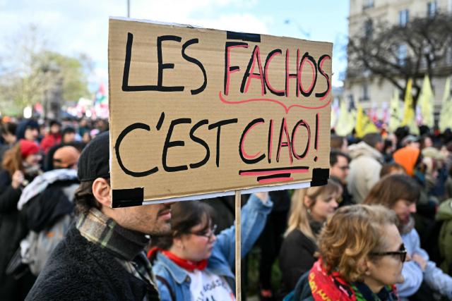 A protester holds a placard during a rally against racism, fascism and state violence, in Paris on March 14, 2026. Some 85 rallies have been announced throughout France for March 14, on the eve of a highly uncertain local election. The vote serves as a test one year ahead of the 2027 presidential election, particularly for the far right, which hopes to build on its momentum. (Photo by Martin LELIEVRE / AFP)