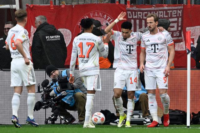 Bayern Munich's English forward #09 Harry Kane (R) celebrates scoring the 1-1 goal with his teammates before the goal was disallowed for handball during the German first division Bundesliga football match between Bayer 04 Leverkusen and FC Bayern Munich in Leverkusen, western Germany on March 14, 2026. (Photo by INA FASSBENDER / AFP) / DFL REGULATIONS PROHIBIT ANY USE OF PHOTOGRAPHS AS IMAGE SEQUENCES AND/OR QUASI-VIDEO