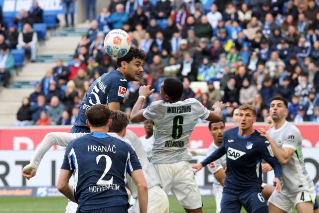 Hoffenheim's Turkish defender #05 Ozan Kabak (L) and Wolfsburg's French defender #06 Jeanuel Belocian (C) vie for a header during the German first division Bundesliga football match between TSG 1899 Hoffenheim and VfL Wolfsburg in Sinsheim, southwestern Germany on March 14, 2026. (Photo by Daniel ROLAND / AFP) / DFL REGULATIONS PROHIBIT ANY USE OF PHOTOGRAPHS AS IMAGE SEQUENCES AND/OR QUASI-VIDEO