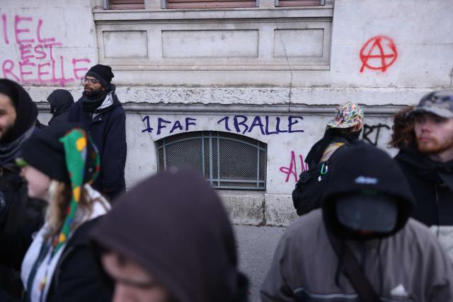 Protesters walk past graffiti reading "One FAF (for facist), one bullet" during a march to protest against racism and fascism in Lyon, southeastern France, on March 14, 2026. Some 85 rallies have been announced throughout France for March 14, on the eve of a highly uncertain local election. The vote serves as a test one year ahead of the 2027 presidential election, particularly for the far right, which hopes to build on its momentum. (Photo by Alex MARTIN / AFP)