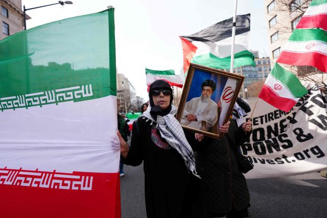 A protestor holds an Iranian flag and a portrait of late Iranian Supreme Leader Ali Khamenei during the International Day of al-Quds (Jerusalem Day) in support of Palestine in front of the White House in Washington, DC, on March 14, 2026. (Photo by Aaron SCHWARTZ / AFP)