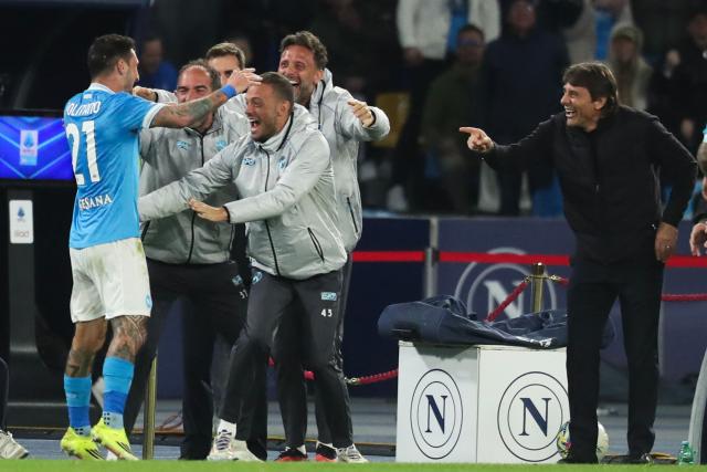 Napoli's Italian forward #21 Matteo Politano (L) celebrates with team members after scoring his team's second goal as Napoli's Italian head coach Antonio Conte (R) looks on during the Italian Serie A football match between Napoli and Lecce at the Diego Armando Maradona stadium in Naples, southern Italy, on March 14, 2026. (Photo by CARLO HERMANN / AFP)