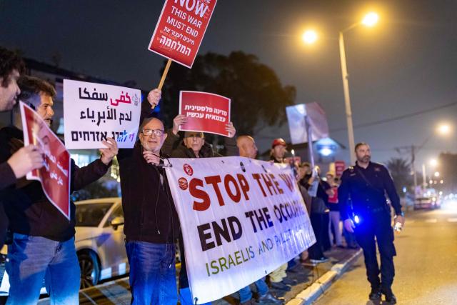 Protestors hold banners during an anti-war protest in Haifa on March 14, 2026. On February 28, Israel and the United States launched strikes on Iran, killing its supreme leader and triggering a war that spread across the Middle East. (Photo by Odd ANDERSEN / AFP) / 