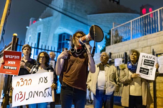 Protestors hold banners during an anti-war protest in Haifa on March 14, 2026. On February 28, Israel and the United States launched strikes on Iran, killing its supreme leader and triggering a war that spread across the Middle East. (Photo by Odd ANDERSEN / AFP) / 