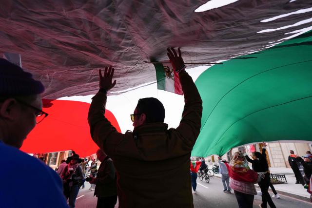 Demonstrators carry a large pre-revolutinary Iranian flag near the White House as they march toward the Lincoln Memorial during the "Human Chain for Iran" rally in Washington, DC, on March 14, 2026. (Photo by Aaron SCHWARTZ / AFP)