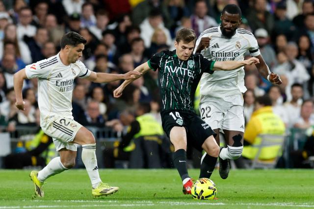 Elche's Spanish midfielder #14 Aleix Febas (C) is challenged by Real Madrid's Moroccan forward #21 Brahim Diaz (L) and Real Madrid's German defender #22 Antonio Ruediger during the Spanish league football match between Real Madrid CF and Elche CF at the Santiago Bernabeu Stadium in Madrid on March 14, 2026. (Photo by Oscar DEL POZO / AFP)
