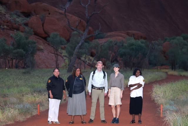 Denmark’s King Frederik X (C) and Queen Mary (2nd R) pose for photographs in front of Uluru, also known as Ayers Rock, during a sunrise visit to the Mu?itjulu Waterhole in Ulu?u-Kata Tju?a National Park on March 15, 2026, part of their five-day state visit to Australia. (Photo by David GRAY / AFP)