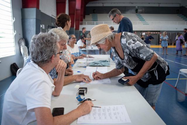 A voter signs a register during the first round of France's 2026 municipal elections at the Anse Vata Sports Arena in Noumea, in the French overseas collectivity of New Caledonia, on March 15, 2026. (Photo by Delphine MAYEUR / AFP)