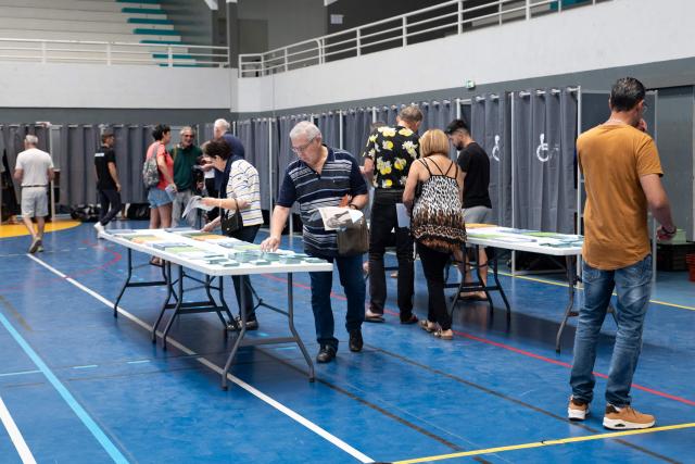 Voters collect electoral slips as they vote during the first round of France's 2026 municipal elections at the Anse Vata Sports Arena in Noumea, in the French overseas collectivity of New Caledonia, on March 15, 2026. (Photo by Delphine MAYEUR / AFP)