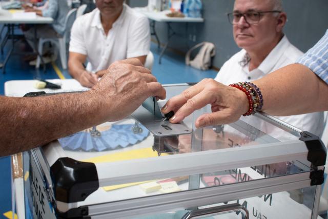 A voters casts their ballot during the first round of France's 2026 municipal elections at the Anse Vata Sports Arena in Noumea, in the French overseas collectivity of New Caledonia, on March 15, 2026. (Photo by Delphine MAYEUR / AFP)