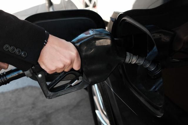 A man holds a fuel pump as he fills his car tank at a gas station in the Manhattan borough of New York, on March 14, 2026. (Photo by CHARLY TRIBALLEAU / AFP)