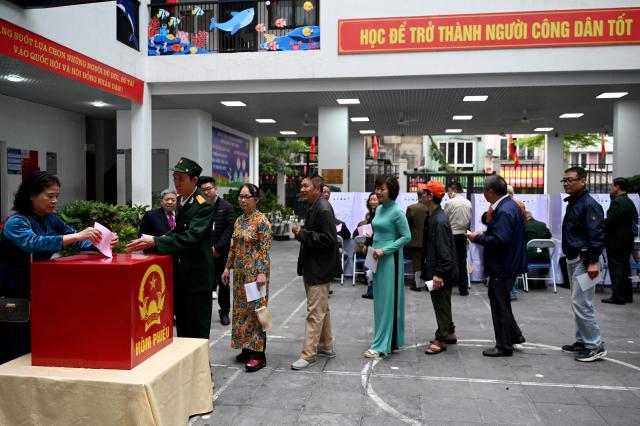 People queue before casting their ballots inside a voting station in Hanoi on March 15, 2026. (Photo by Nhac NGUYEN / AFP)