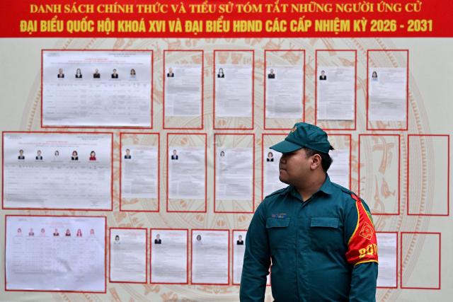 An election official stands next to lists of candidates inside a voting station in Hanoi on March 15, 2026. Polls opened in Vietnam with voters casting ballots for members of the National Assembly, the country's top legislative body that serves mainly to ratify decisions by the ruling Communist Party. (Photo by Nhac NGUYEN / AFP)
