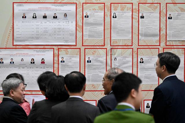 People look at the lists of candidates inside a voting station in Hanoi on March 15, 2026. Polls opened in Vietnam with voters casting ballots for members of the National Assembly, the country's top legislative body that serves mainly to ratify decisions by the ruling Communist Party. (Photo by Nhac NGUYEN / AFP)