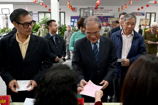 Vietnam's former National Assembly chairman Nguyen Sinh Hung (C) Receives his ballot papers at a voting station in Hanoi on March 15, 2026. Polls opened in Vietnam with voters casting ballots for members of the National Assembly, the country's top legislative body that serves mainly to ratify decisions by the ruling Communist Party. (Photo by Nhac NGUYEN / AFP)