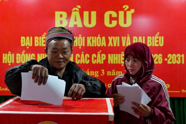 Ethnic minority citizens cast their votes inside a polling station in the northern Vietnamese province of Tuyen Quang on March 15, 2026. Polls opened in Vietnam with voters casting ballots for members of the National Assembly, the country's top legislative body that serves mainly to ratify decisions by the ruling Communist Party. (Photo by -STR / AFP)