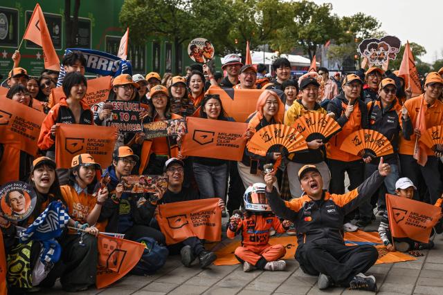 Supporters of team McLaren pose as they arrive for the Formula One Chinese Grand Prix at the Shanghai International Circuit in Shanghai on March 15, 2026. (Photo by Jade GAO / AFP)