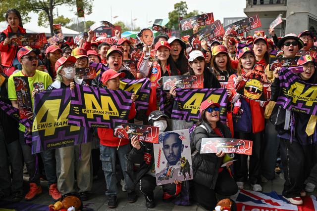 Supporters of Ferrari's British driver Lewis Hamilton pose as they arrive for the Formula One Chinese Grand Prix at the Shanghai International Circuit in Shanghai on March 15, 2026. (Photo by Jade GAO / AFP)