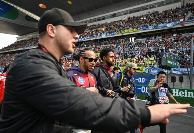 Ferrari's British driver Lewis Hamilton (2nd L) walks to pose in front of his supporters prior to the Formula One Chinese Grand Prix at the Shanghai International Circuit in Shanghai on March 15, 2026. (Photo by Greg Baker / AFP)