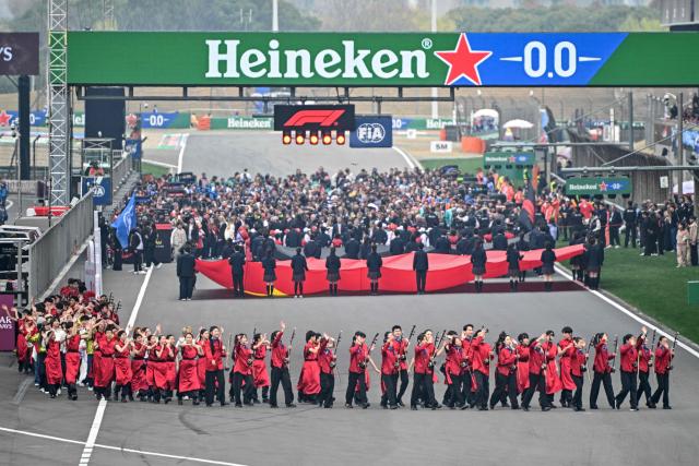 Performers gather in the track before the start of the Formula One Chinese Grand Prix at the Shanghai International Circuit in Shanghai on March 15, 2026. (Photo by HECTOR RETAMAL / AFP)