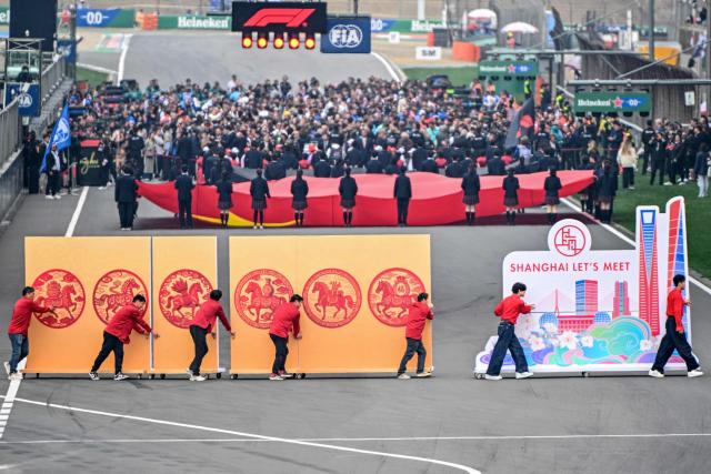 Performers gather in the track before the start of the Formula One Chinese Grand Prix at the Shanghai International Circuit in Shanghai on March 15, 2026. (Photo by HECTOR RETAMAL / AFP)