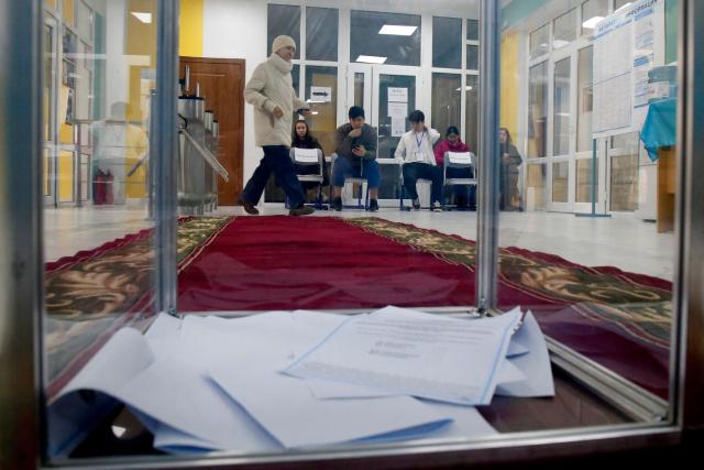 A woman walks past a ballot box at a polling station during the constitutional referendum in Almaty on March 15, 2026. (Photo by Ruslan PRYANIKOV / AFP)