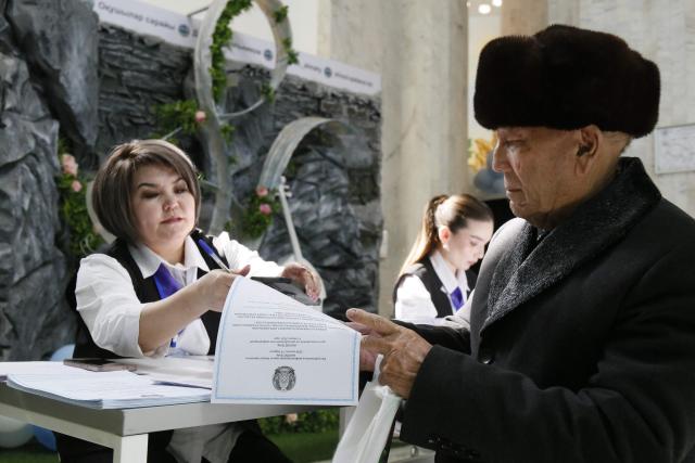 A man receives a ballot at a polling station during the constitutional referendum in Almaty on March 15, 2026. (Photo by Ruslan PRYANIKOV / AFP)