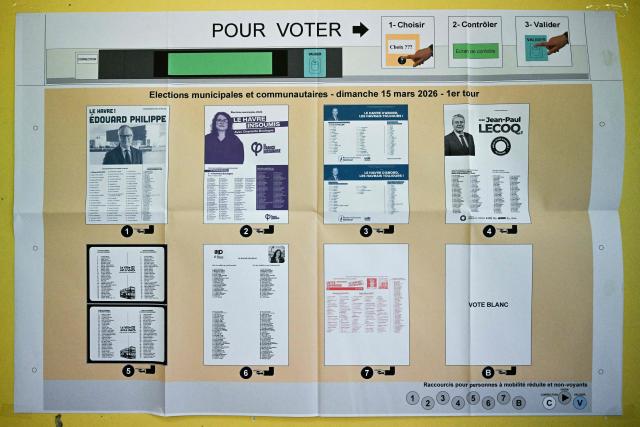 This photograph taken on March 15, 2026, shows a poster explaining how to cast a vote on an electronic voting machine, at a voting station during the first round of France's 2026 municipal elections in Le Havre, northeastern France. (Photo by Lou BENOIST / AFP)