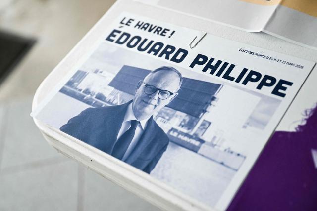 This photograph taken on March 15, 2026, shows a campaign leaflet picturing Le Havre incumbent mayor and center-right Horizons party candidate for his re-election Edouard Philippe displayed at a voting station during the first round of France's 2026 municipal elections in Le Havre, northeastern France. (Photo by Lou BENOIST / AFP)