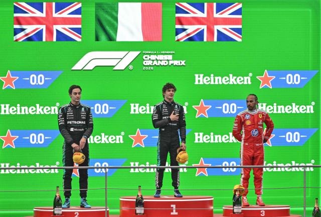 Winner Mercedes' Italian driver Kimi Antonelli (C), second-placed Mercedes' British driver George Russell (L) and third-placed Ferrari's British driver Lewis Hamilton (R) celebrate on the podium after the Formula One Chinese Grand Prix at the Shanghai International Circuit in Shanghai on March 15, 2026. (Photo by HECTOR RETAMAL / AFP)