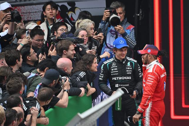 Winner Mercedes' Italian driver Kimi Antonelli (2nd R) and third-placed Ferrari's British driver Lewis Hamilton (R) speak after the Formula One Chinese Grand Prix at the Shanghai International Circuit in Shanghai on March 15, 2026. (Photo by HECTOR RETAMAL / AFP)