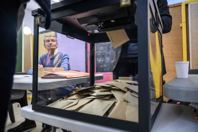 An official watches as voters cast their ballot during the first round of France's 2026 municipal elections in Perpignan, southern France, on March 15, 2026. (Photo by Ed JONES / AFP)