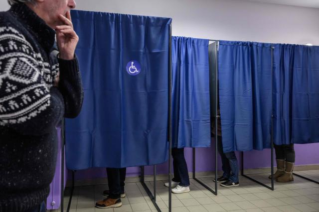 Voters prepare their ballot in polling booths prior to cast their vote during the first round of France's 2026 municipal elections in Perpignan, southern France, on March 15, 2026. (Photo by Ed JONES / AFP)