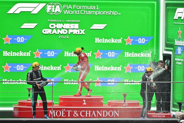 Winner Mercedes' Italian driver Kimi Antonelli (R), second-placed Mercedes' British driver George Russell (L) and third-placed Ferrari's British driver Lewis Hamilton (C) celebrate on the podium after the Formula One Chinese Grand Prix at the Shanghai International Circuit in Shanghai on March 15, 2026. (Photo by Hector RETAMAL / AFP)