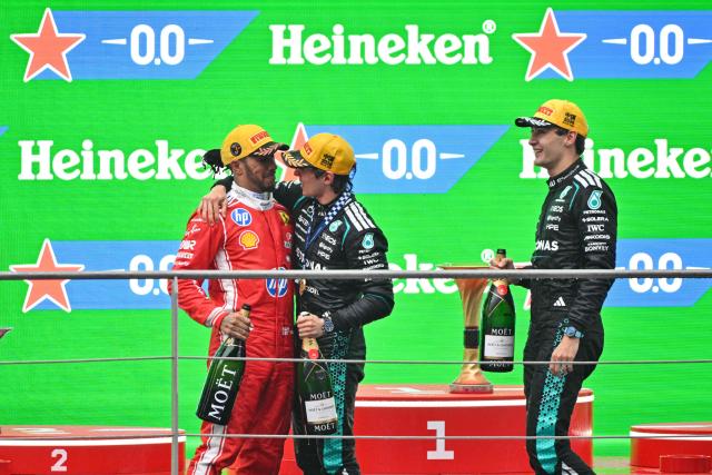 Winner Mercedes' Italian driver Kimi Antonelli (C), second-placed Mercedes' British driver George Russell (R) and third-placed Ferrari's British driver Lewis Hamilton (L) celebrate on the podium after the Formula One Chinese Grand Prix at the Shanghai International Circuit in Shanghai on March 15, 2026. (Photo by Hector RETAMAL / AFP)