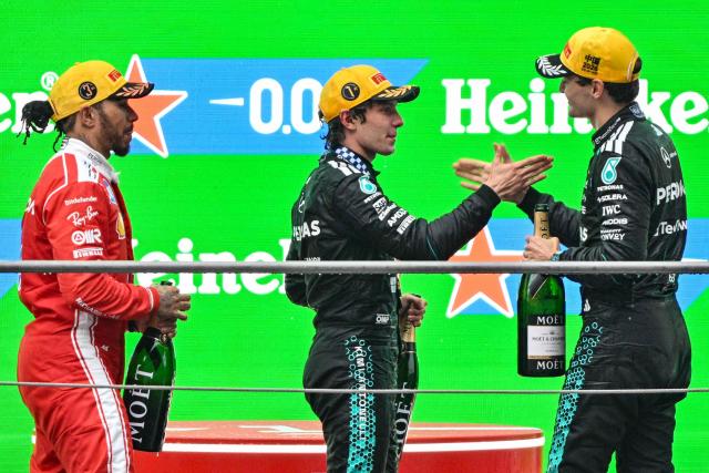 Winner Mercedes' Italian driver Kimi Antonelli (C), second-placed Mercedes' British driver George Russell (R) and third-placed Ferrari's British driver Lewis Hamilton (L) celebrate on the podium after the Formula One Chinese Grand Prix at the Shanghai International Circuit in Shanghai on March 15, 2026. (Photo by Hector RETAMAL / AFP)