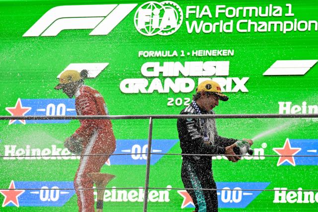 Winner Mercedes' Italian driver Kimi Antonelli (R) and third-placed Ferrari's British driver Lewis Hamilton celebrate on the podium after the Formula One Chinese Grand Prix at the Shanghai International Circuit in Shanghai on March 15, 2026. (Photo by Jade Gao / AFP)