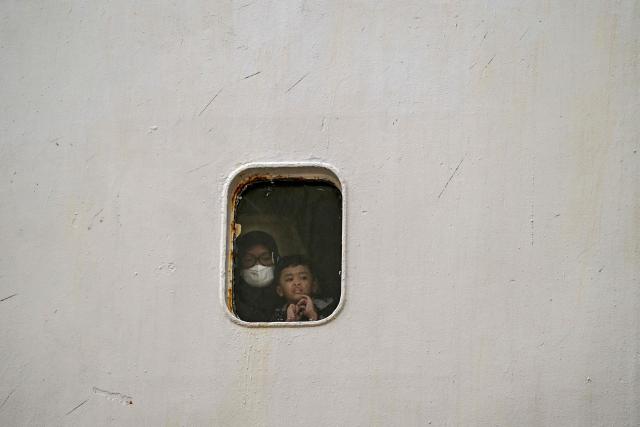 Passengers look out from a porthole of a ferry before disembarking at the Perak seaport in Surabaya on March 15, 2026, as people travel to their hometowns ahead of Eid al-Fitr which marks the end of the Muslim holy fasting month of Ramadan. (Photo by JUNI KRISWANTO / AFP)