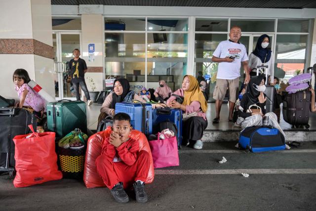 Passengers wait for transportation after disembarking from a ferry at the Perak seaport in Surabaya on March 15, 2026, as people travel to their hometowns ahead of Eid al-Fitr which marks the end of the Muslim holy fasting month of Ramadan. (Photo by JUNI KRISWANTO / AFP)
