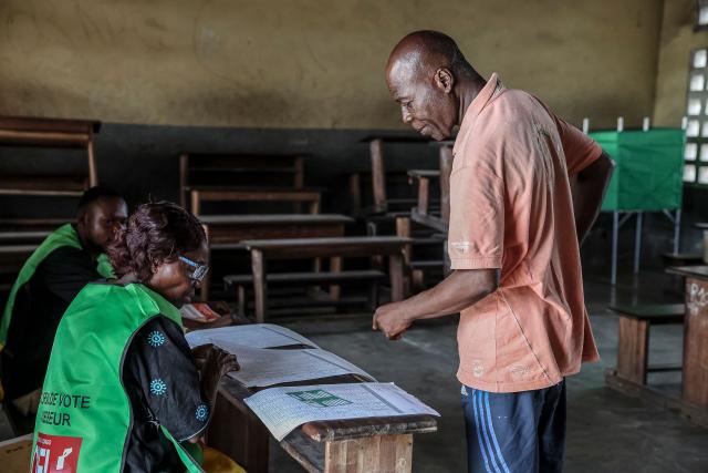 An electoral agent checks a voter's information at a polling station in Brazzaville on March 15, 2026 during the Republic of Congo's presidential elections. (Photo by Daniel BELOUMOU OLOMO / AFP)