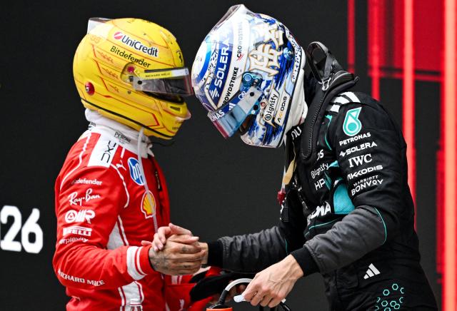 Third-placed Ferrari's British driver Lewis Hamilton (L) and second-placed Mercedes' British driver George Russell shake hands after the Formula One Chinese Grand Prix at the Shanghai International Circuit in Shanghai on March 15, 2026. (Photo by GREG BAKER / AFP)