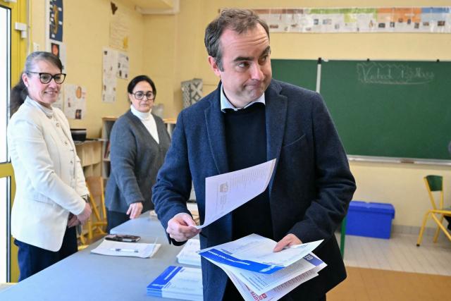 France's Prime Minister Sebastien Lecornu, a candidate on the broad right-wing list "Generations Vernon", grabs ballots during the first round of France's 2026 municipal elections in Vernon, northwestern France, on March 15, 2026. (Photo by Martin LELIEVRE / POOL / AFP)