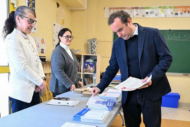 France's Prime Minister Sebastien Lecornu, a candidate on the broad right-wing list "Generations Vernon", grabs ballots during the first round of France's 2026 municipal elections in Vernon, northwestern France, on March 15, 2026. (Photo by Martin LELIEVRE / POOL / AFP)