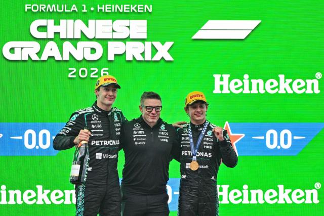Winner Mercedes' Italian driver Kimi Antonelli (R), second-placed Mercedes' British driver George Russell (L) and Mercedes' race engineer Peter Bonnington (C) celebrate on the podium after the Formula One Chinese Grand Prix at the Shanghai International Circuit in Shanghai on March 15, 2026. (Photo by Hector RETAMAL / AFP)