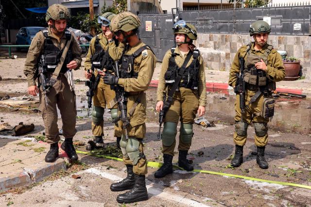 Israeli army soldiers gather at the site of a projectile impact from an Iranian strike in southern Tel Aviv on March 15, 2026. On February 28, Israel and the United States launched strikes on Iran, killing its supreme leader Ayatollah and triggering a war that spread across the Middle East. (Photo by Jack GUEZ / AFP) / 