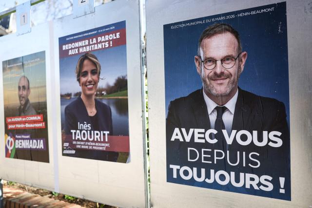 A photograph taken on March 15, 2026 shows an a campaign poster picturing Incumbent mayor of Henin-Beaumont and far-right Rassemblement National (RN) party mayoral candidate Steeve Briois (R) and left-wing Socialist Party for "Divers Gauche" mayoral candidate Ines Taourit (C)  during the first round of France's 2026 municipal elections in Henin-Beaumont, northern France. (Photo by Sameer AL-DOUMY / AFP)